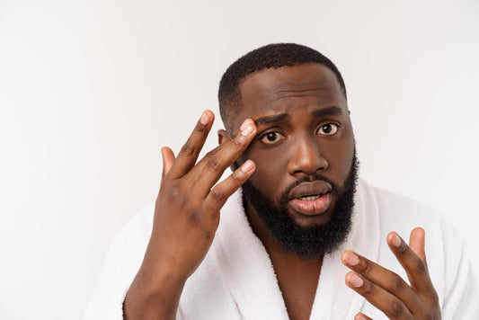 Handsome black man checking his face for skin issues