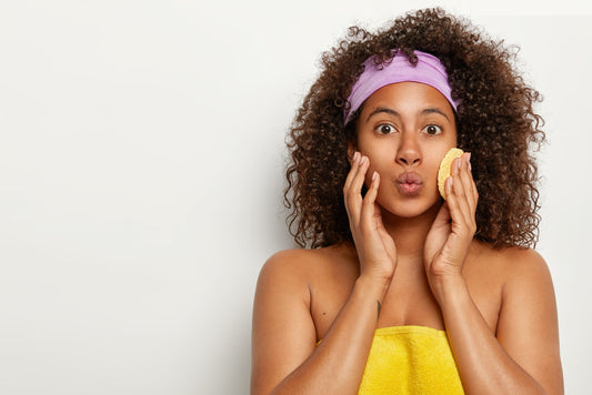 Mastering Clear Skin: Understanding Acne, Clogged Pores, and Achieving a Flawless Melanin Complexion-good-looking-curly-woman-keeps-lips-folded-wrapped-soft-towel-wants-have-smooth-fresh-skin-uses-cosmetic-sponge-wiping-face-wears-headband